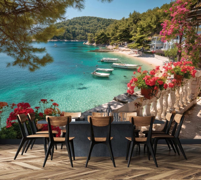 Fototapete mit mediterraner Küstenlandschaft, Booten auf türkisem Wasser und einem blühenden Balkon hinter einem Esstisch.