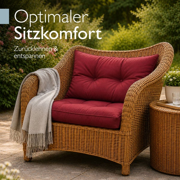 Komfortabler Garten-Loungesessel aus Polyrattan mit roten Polstern und einer grauen Decke auf einer hellen Terrasse.