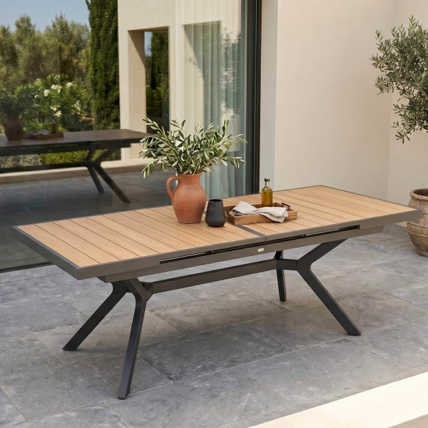 Moderner ausziehbarer Gartentisch mit Holzlatten-Platte und anthrazitfarbenem Metallgestell auf einer hellen Steinterrasse vor einem Wohnhaus.
