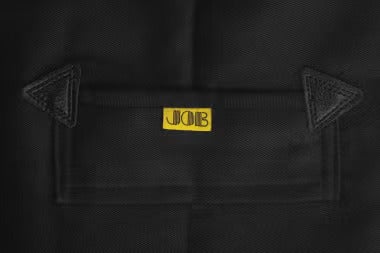 Detailansicht einer Tasche an einer schwarzen Arbeitshose mit Lederverstärkungen und JOB Logo.