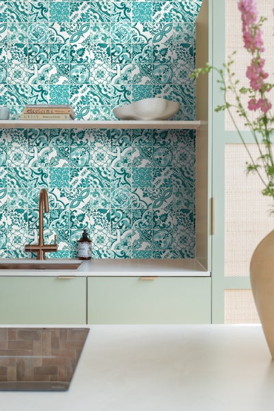 Küchenszene mit Wandfliesen im Vintage-Stil, Spüle und Küchenutensilien auf einer Arbeitsfläche.