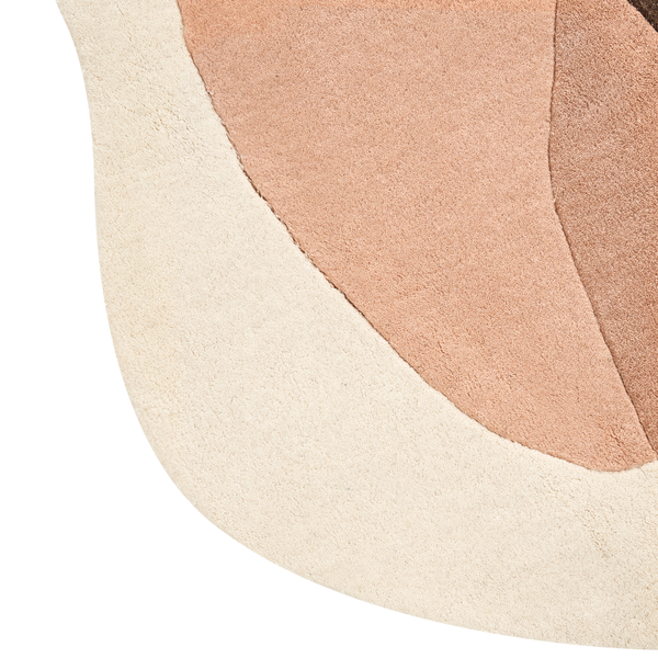 Detail eines getufteten Teppichs mit geschwungenem Rand und mehrfarbigem Muster in Beige und Braun.