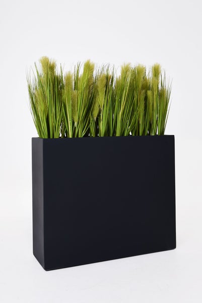Künstliches Gras mit Federwedeln in einem rechteckigen schwarzen Pflanzgefäß.