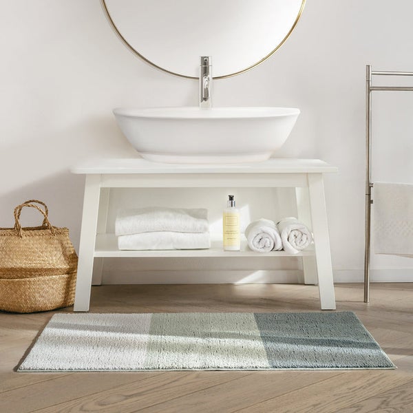 Badezimmer mit Waschbecken, Spiegel, Handtüchern und Badteppich