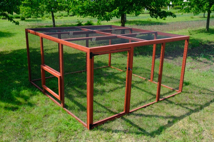 Freilaufgehege für Kleintiere mit Holzrahmen und Drahtgitter, auf einer Rasenfläche in einem Garten stehend.