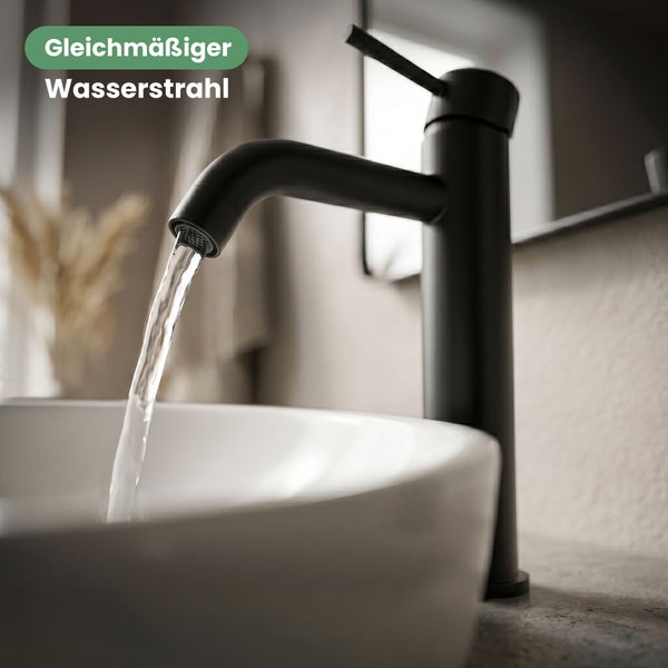 Schwarze Waschtischarmatur mit gleichmäßigem Wasserstrahl über einem weißen Waschbecken.