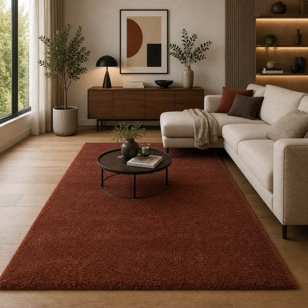 Modernes Wohnzimmer mit großem, rostbraunem Hochflorteppich auf hellem Holzboden neben beigem Ecksofa und schwarzem Couchtisch.