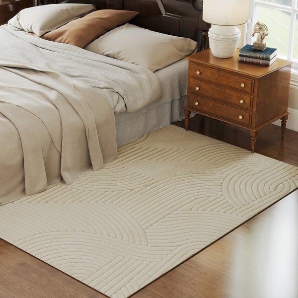 Beiger Teppich mit geometrischem Linienmuster in einem Schlafzimmer neben einem Bett und einem hölzernen Nachttisch.