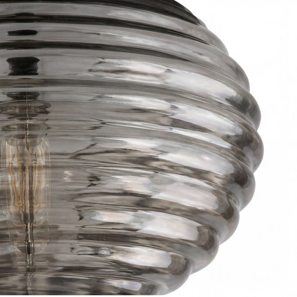 Nahaufnahme eines geriffelten Lampenschirms aus Glas mit sichtbarem Leuchtmittel.