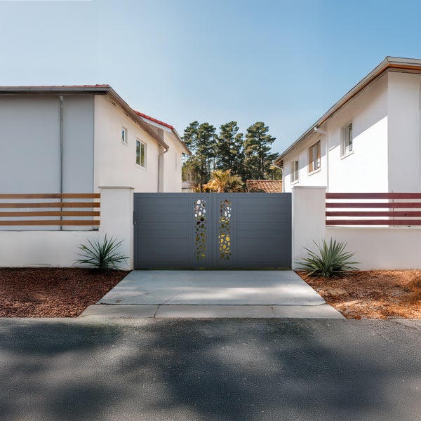 Graues zweiflügeliges Einfahrtstor aus Aluminium mit horizontalen Paneelen und dekorativem Blättermuster in der Mitte zwischen weißen Pfeilern.