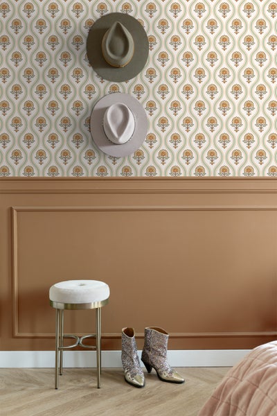 Dekoratives Interieur mit gemusterter Tapete, zwei Hüten, einem Hocker und Stiefeln