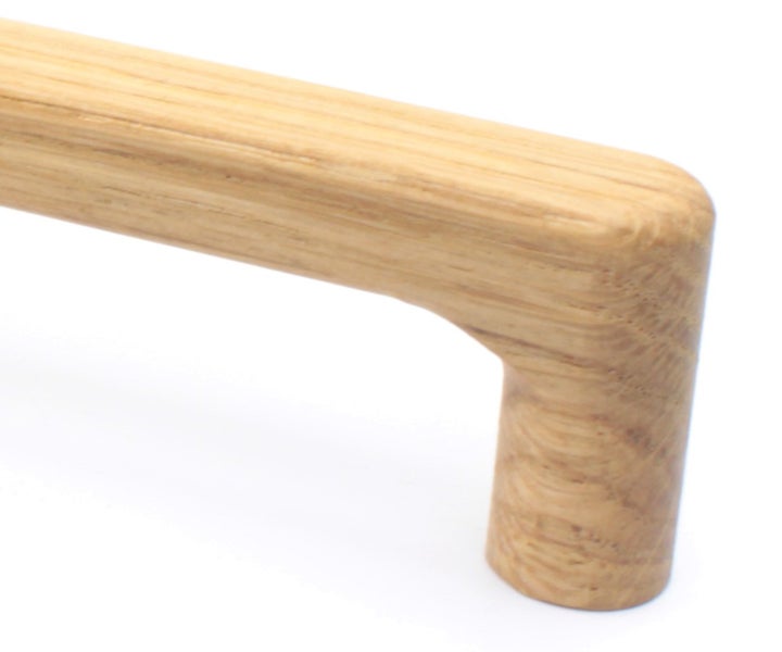 Nahaufnahme eines abgerundeten Möbelgriffs aus Holz mit sichtbarer Maserung.