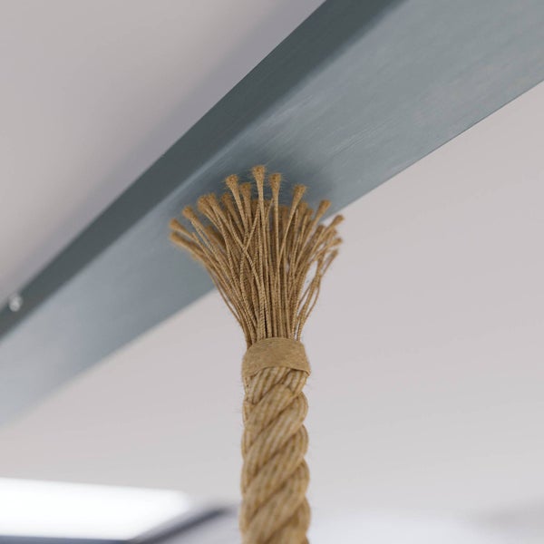 Nahaufnahme eines gedrehten Naturseils, das an einem dunklen Metallbalken befestigt ist.