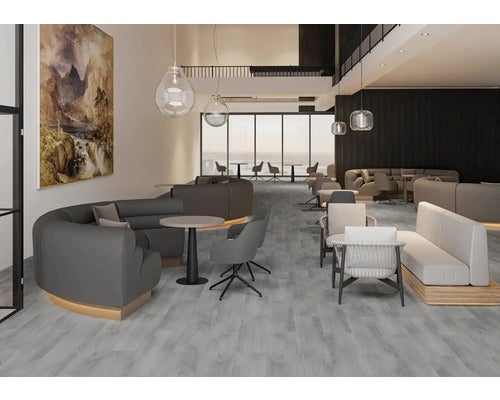 Moderner Loungebereich mit grauem Bodenbelag in Holzoptik, geschwungenen Sofas, Sesseln und großen Fensterfronten.