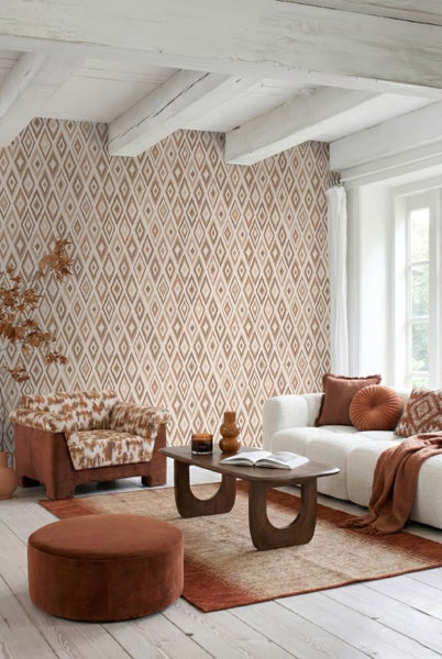Vliestapete mit geometrischem Rautenmuster in einem hellen, gemütlichen Wohnzimmer mit Holzmöbeln und weichen Textilien.