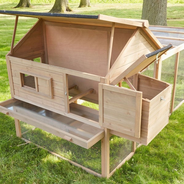 Großer Kaninchenstall aus Holz mit mehreren Etagen, stabilen Drahtgittern und Bitumendach im Garten mit einem Kind und Kaninchen.