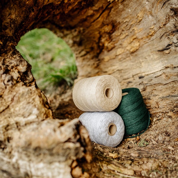 Drei Rollen Kordel für Bastelarbeiten und Macramé in einem hohlen Baumstamm.