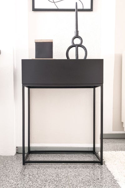Schwarzer Pflanzkasten aus Metall auf einem schmalen Gestell im minimalistischen Design.