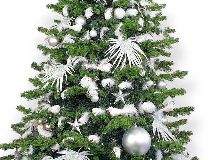 Ein künstlicher Weihnachtsbaum geschmückt mit Kugeln, Sternen, dekorativen Vögeln und Federornamenten in einer weihnachtlichen Atmosphäre.