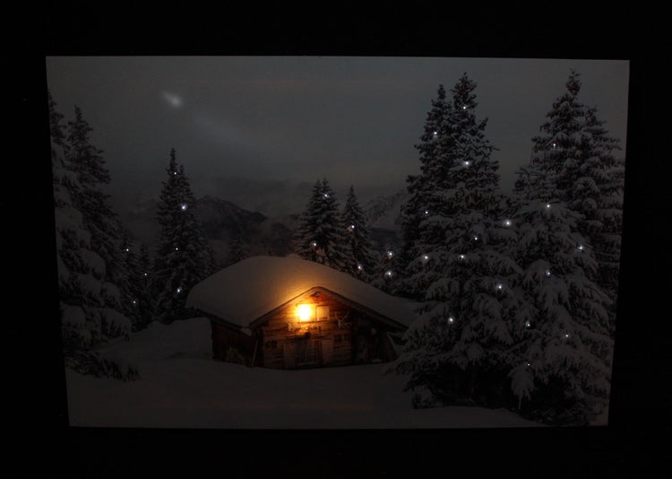 Dekoratives Weihnachtsbild mit beleuchteter Hütte im verschneiten Winterwald.