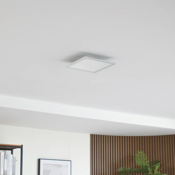 Quadratisches LED-Panel an einer weißen Decke montiert in einem hellen, modern eingerichteten Raum.