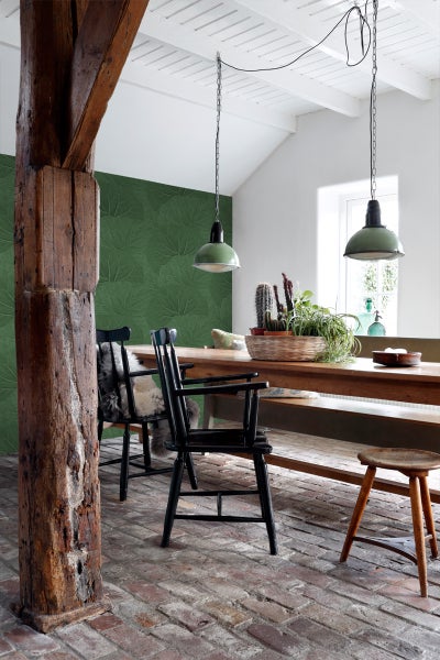 Esszimmer mit Holztisch, Stühlen, Hängelampen und Blattmuster-Tapete.