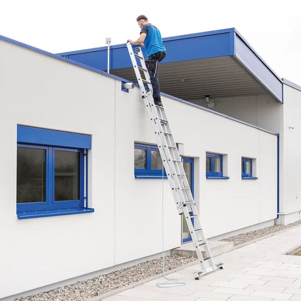 Eine Person benutzt eine Mehrzweckleiter aus Aluminium an einem Gebäude.
