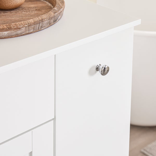 Detailaufnahme eines weißen Badezimmerschranks mit Schubladen und einem runden, silberfarbenen Griff