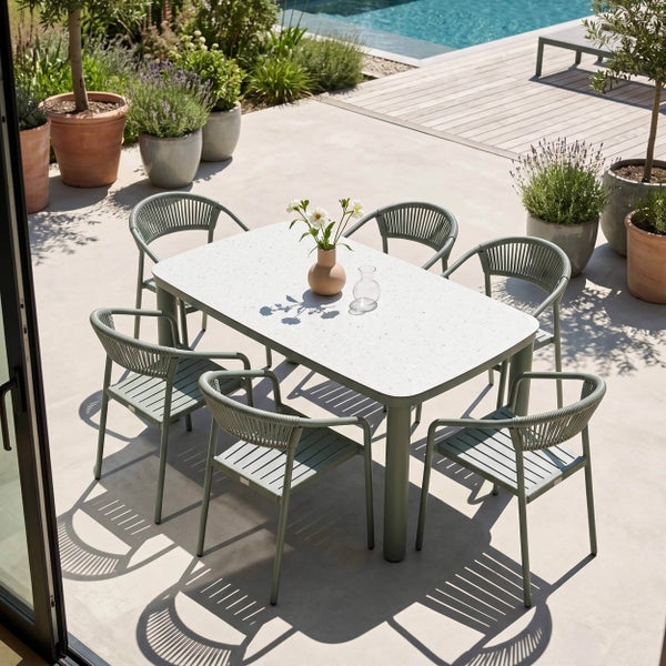 Modernes Gartenmöbel-Set mit rechteckigem Tisch mit gesprenkelter Platte und sechs grünen Gartenstühlen auf einer hellen Terrasse am Pool.