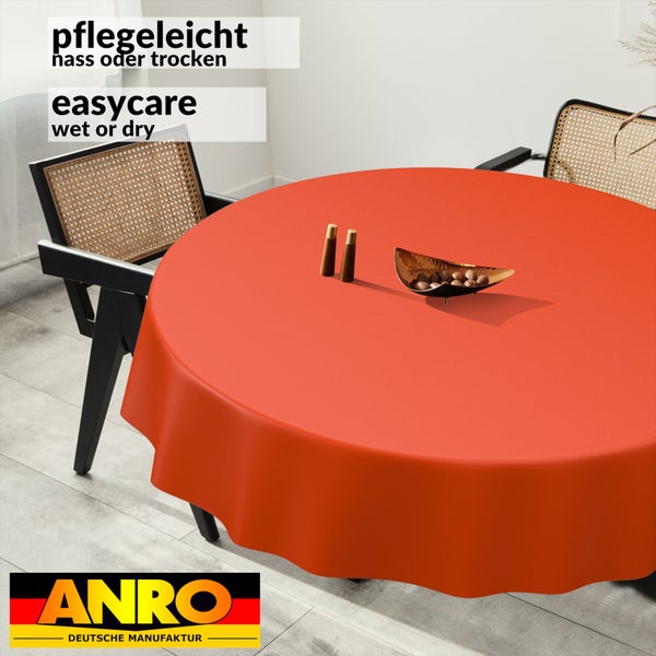 Runde, pflegeleichte Tischdecke in Orange auf einem Esstisch, nass oder trocken abwischbar, ANRO Logo.