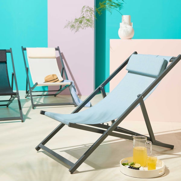 Moderne Liegestühle mit Metallgestell, Textilbespannung und Kopfstütze in einer hellen, sommerlichen Szene.