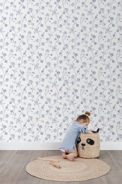 Vliestapete mit blauem Blumenmuster aus Rosen und Ranken im Kinderzimmer, kombiniert mit Naturteppich und Panda-Korb.