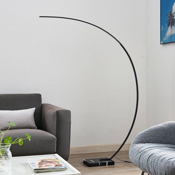Moderne schwarze Bogenstehlampe mit schmalem, gebogenem Arm und Marmorfuß im Wohnzimmer neben einem grauen Sofa.