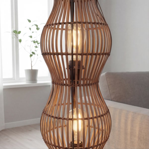 Stehleuchte aus Holzgeflecht mit zwei sichtbaren Leuchtmitteln in einem hell eingerichteten Wohnzimmer neben einem Sofa.