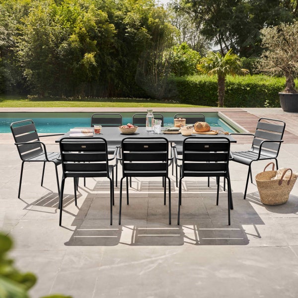 Modernes Gartenmöbel-Set aus grauem Metall mit einem rechteckigen Tisch und acht Stühlen auf einer hellen Terrasse neben einem Pool.