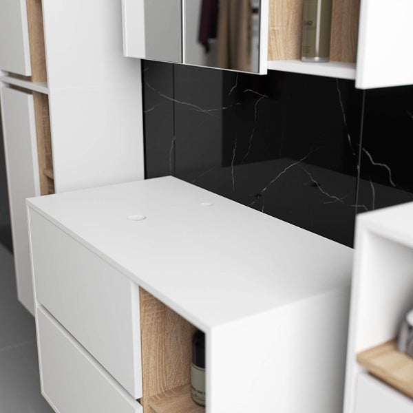 Detailaufnahme eines Badezimmers mit weißen Unterschränken und einer schwarzen Marmor Rückwand