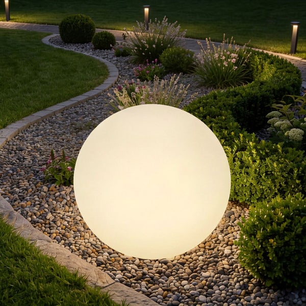 Große, leuchtende Gartenkugelleuchte in einem modern gestalteten Garten mit Kiesbett, Sträuchern und Rasenfläche bei Nacht.