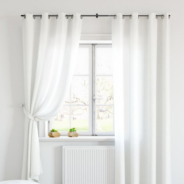 Ein weißer Ösenvorhang hängt an einer Vorhangstange vor einem Fenster. Ein Vorhang ist zur Seite gerafft, vor dem Fenster stehen zwei Sukkulenten.