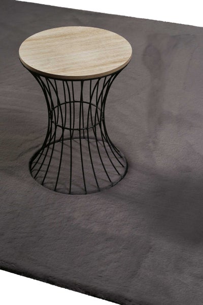 Runder Beistelltisch mit Holzplatte und schwarzem Metalldrahtgestell auf einem grauen Teppich.