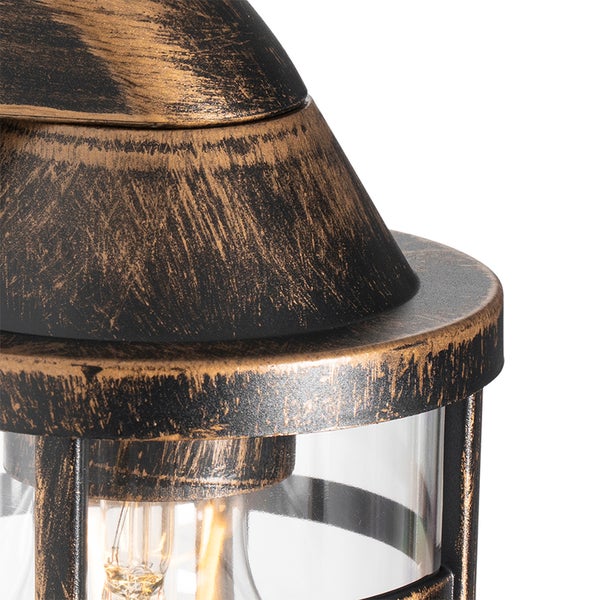 Nahaufnahme einer Außenleuchte im antiken Design mit schwarz-goldener Patina, Metallgestell und Klarglas.