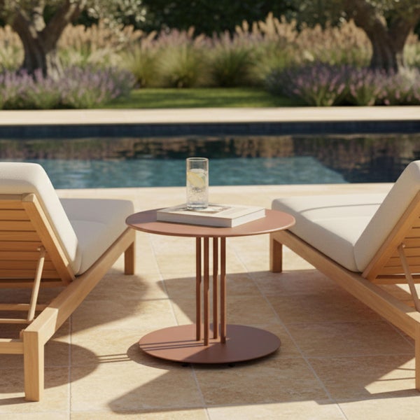 Moderner Beistelltisch aus Metall zwischen zwei Holz-Sonnenliegen am Pool in einem hellen Garten.