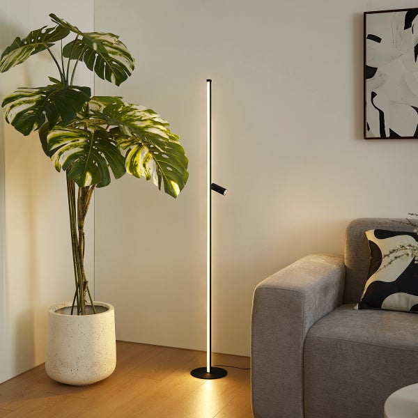 Moderne, minimalistische schwarze LED-Stehlampe mit vertikalem Lichtband und verstellbarem Spot in einem hellen, organisierten Wohnzimmer.