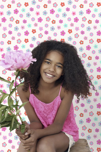 Lächelndes Mädchen mit Blume vor Blumentapete