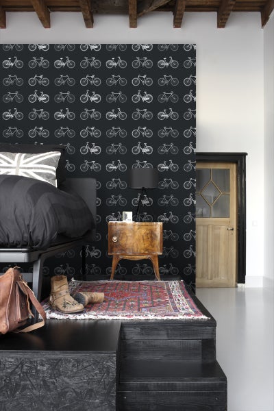 Schlafzimmer mit Bett, Nachttisch, Teppich und Tapete mit Fahrradmuster