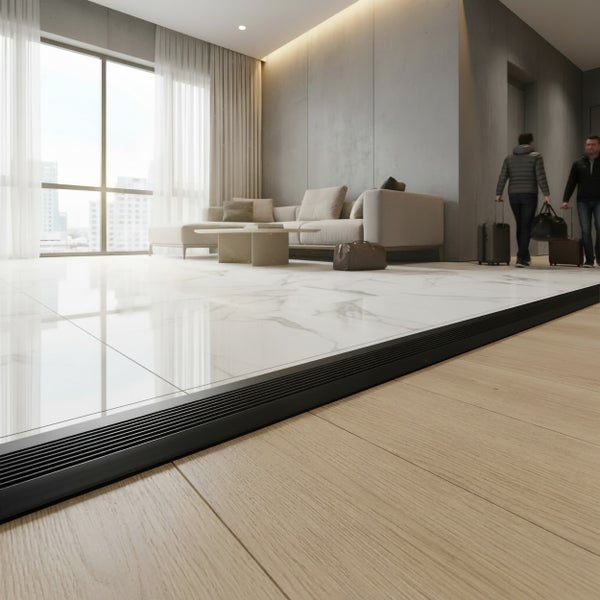 Moderne Wohnraumgestaltung mit Übergang zwischen Marmorfliesen und Holzboden mittels schwarzer Bodenabschlussprofilschiene.