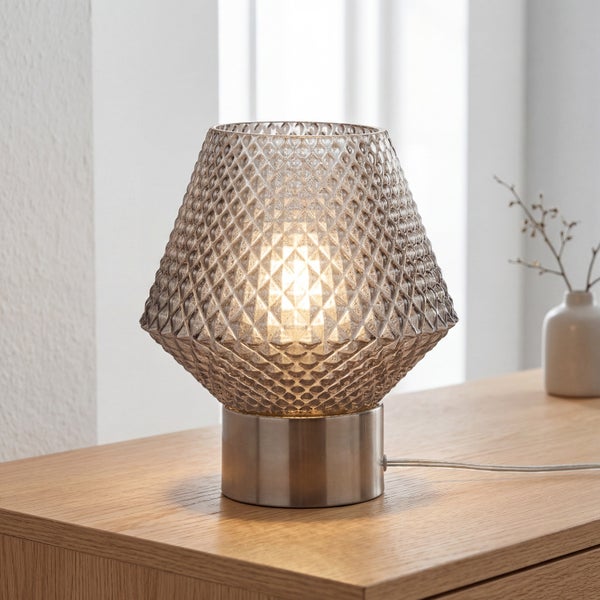Tischleuchte mit strukturiertem Glasschirm und metallem Sockel auf einem Holztisch