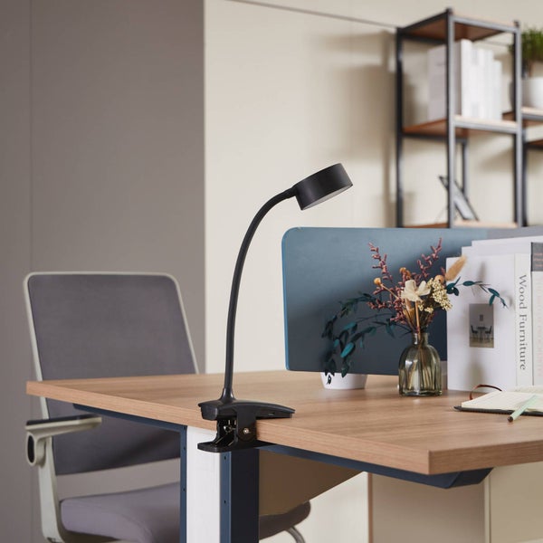 Schwarze LED-Klemmlampe mit flexiblem Hals an einem Schreibtisch aus Holz befestigt.