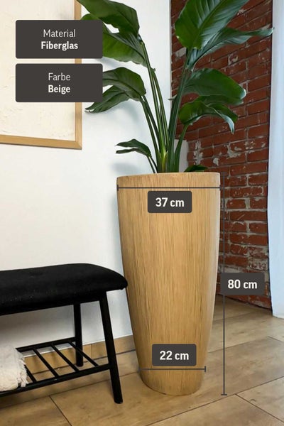 Hoher beige Pflanzkübel aus Fiberglas, 80 Zentimeter hoch, 37 Zentimeter breit oben, 22 Zentimeter unten, neben einer schwarzen Sitzbank.
