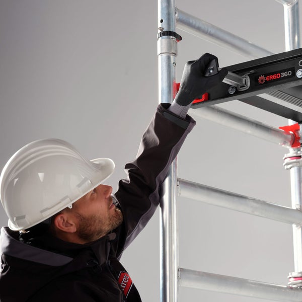 Ein Mann mit Schutzhelm montiert ein Gerüst