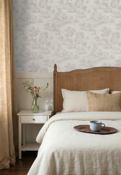 Vliestapete mit klassischem Toile de Jouy Muster in einem hellen Schlafzimmer mit Holzbett und weißem Nachttisch.